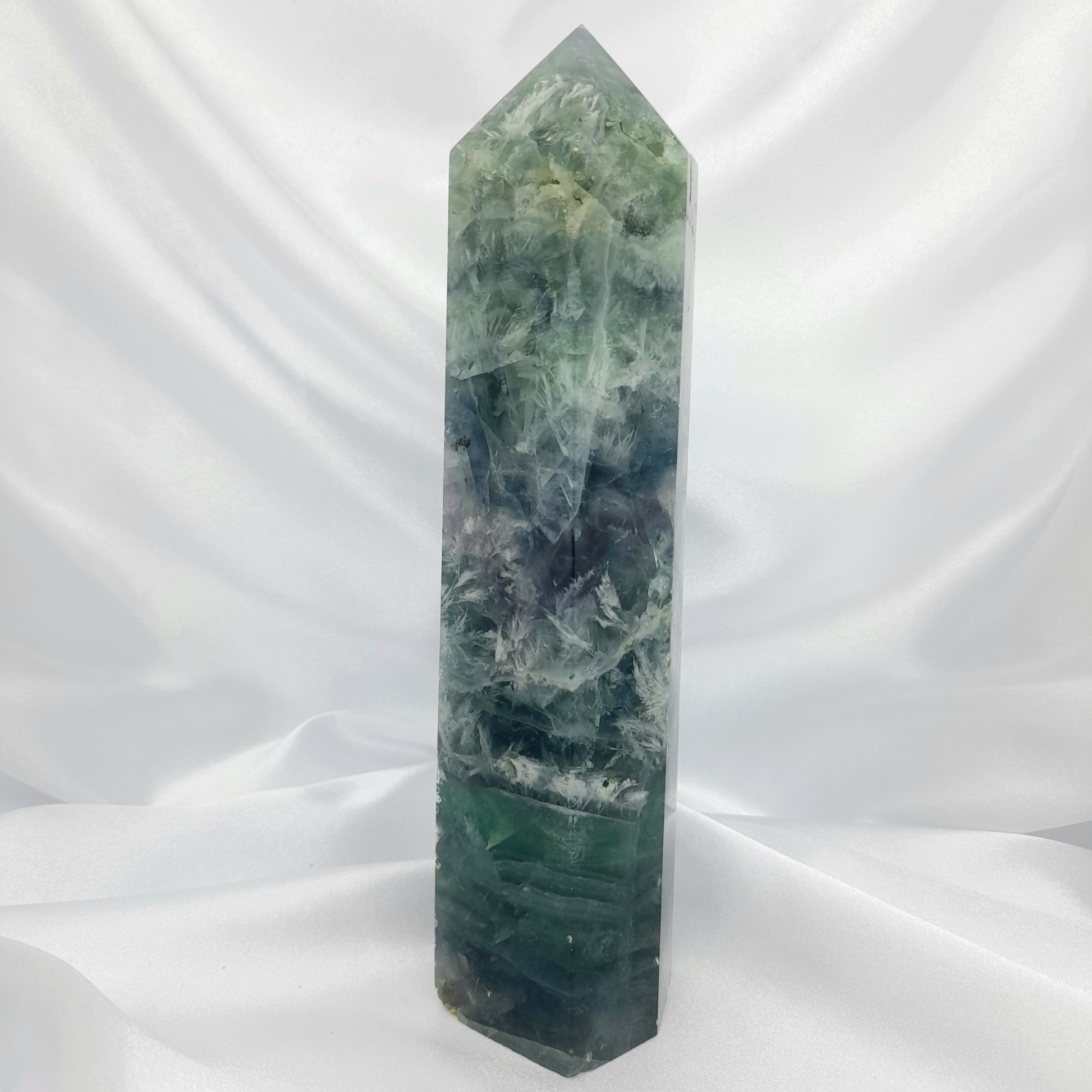 Fluorite Large Tower: A majestic crystal standing roughly 20cm tall and weighing 925g. Known for its balancing energy and transformative properties, Fluorite brings positivity and enlightenment into your space. This special piece features gorgeous druzies and flashy rainbows, making it a unique and visually stunning addition to your collection.